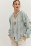 Embroidered long raglan sleeve top featuring V-neck with braided tassel tie. Elasticated cuffs with ruffle trim. Unlined. Woven. Non-sheer. Lightweight.